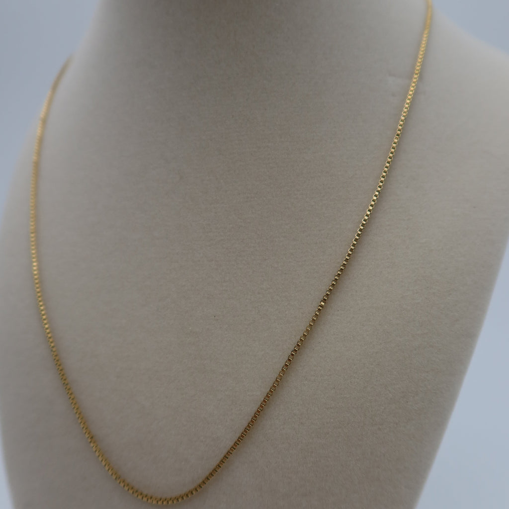 Gold chain necklace on a mannequin bust against a plain background
