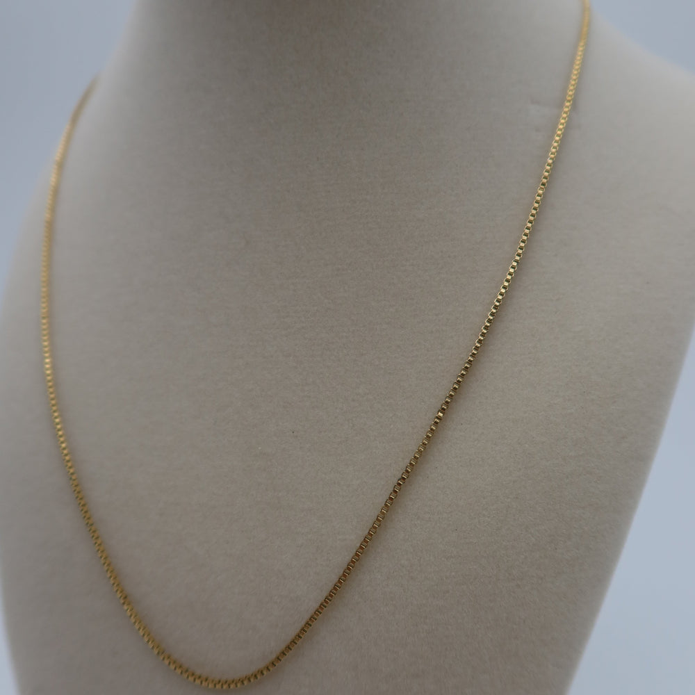 Gold chain necklace on a mannequin bust against a plain background